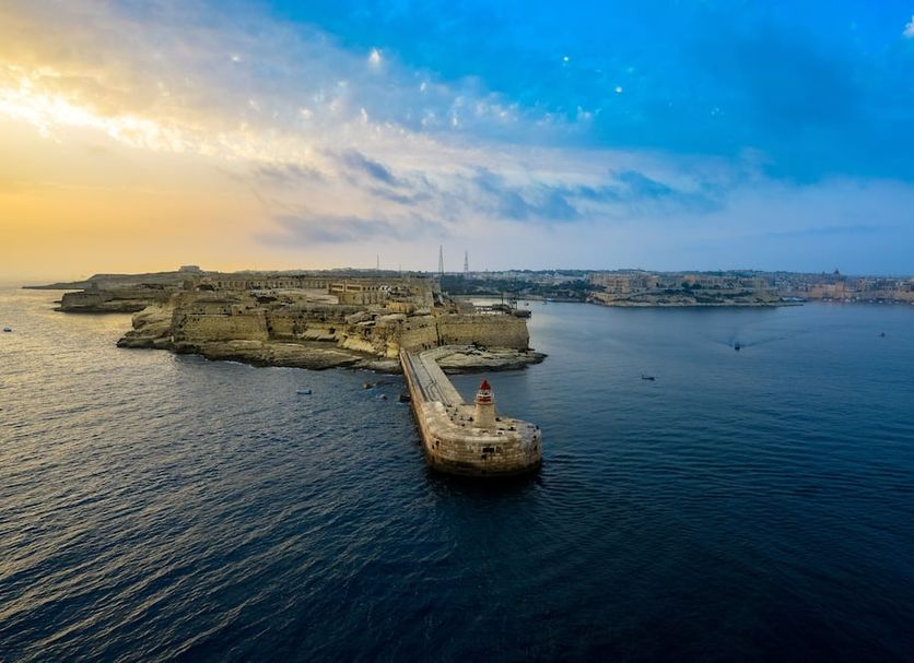 Ddream Hotel, St. Julian's, with a harbor view at sunset and a stone breakwater leading into the sea
