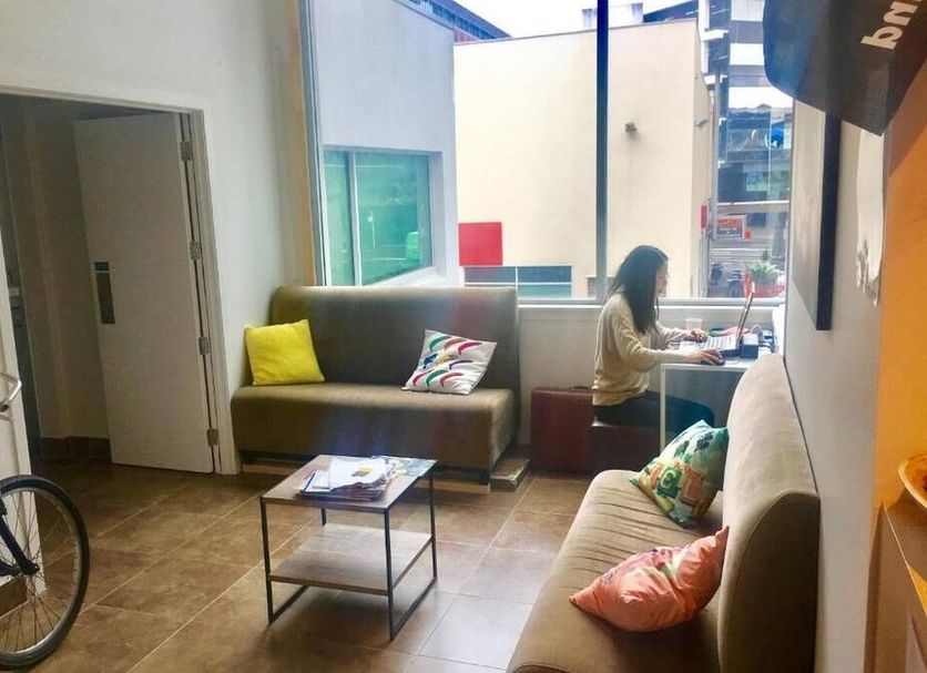 Metro Adventurer Backpackers Auckland common lounge with sofas, coffee table, bicycle and street view