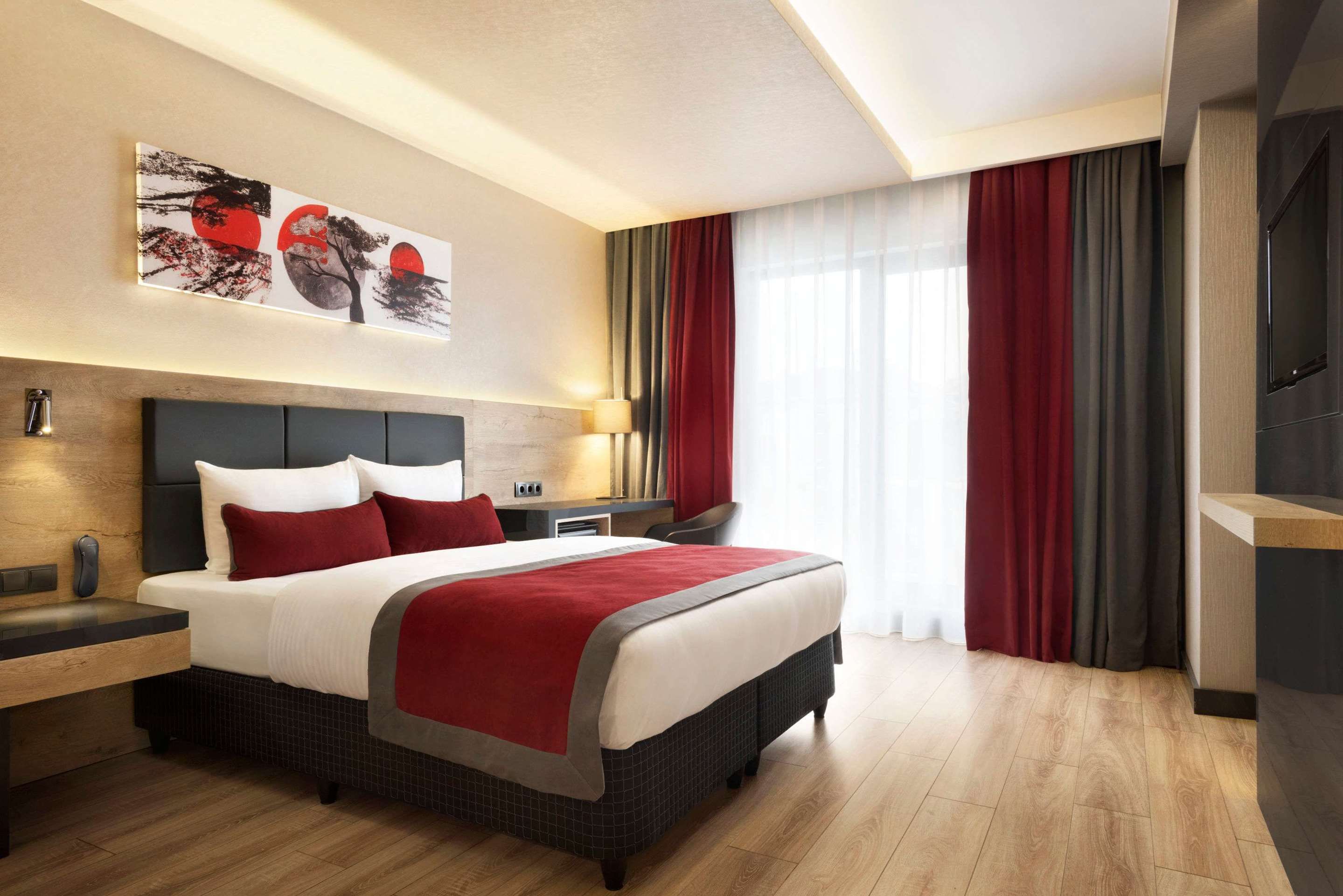 Ramada Encore by Wyndham Gebze room with king bed, red accents, and floor-to-ceiling window