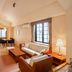 Colosseum Inn Tateshina living room with staircase, sofa, armchairs, desk, and large window in Tateshina