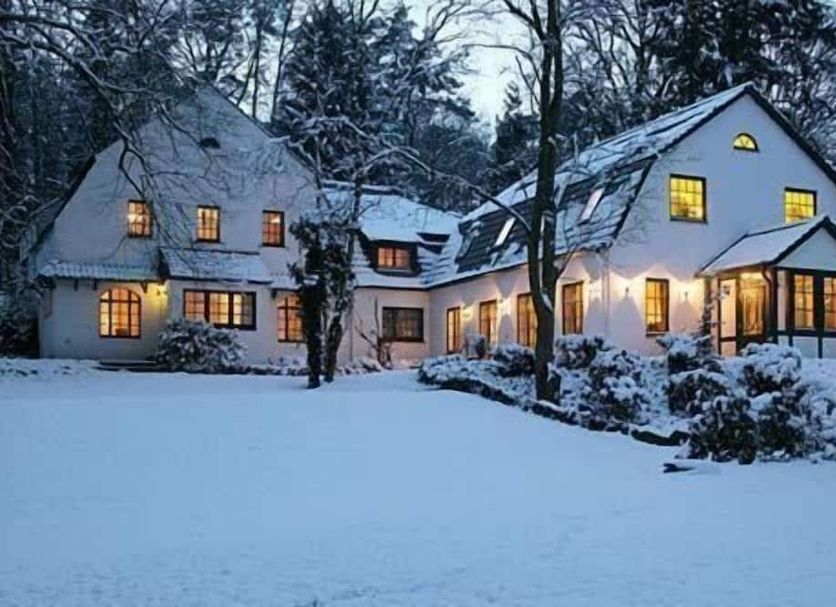 Hotel Buchenhof in Worpswede, snow-covered hotel exterior with lit windows at dusk
