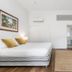 Cove Studios Byron Bay room with king bed, desk, woven rug and open doorway to bathroom