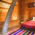 The Yuppi Hippi Beachpackers Hostel, Anjuna: cozy wooden guest room with red bedspread and striped rug