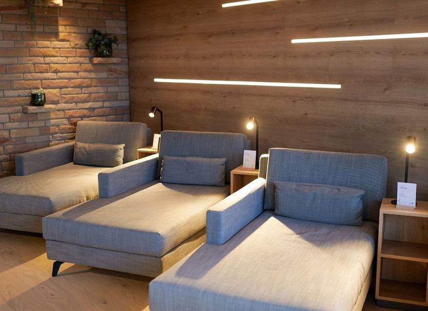 Leinsweiler Hof in Leinsweiler: modern lounge with three gray chaise-style chairs and brick accent wall
