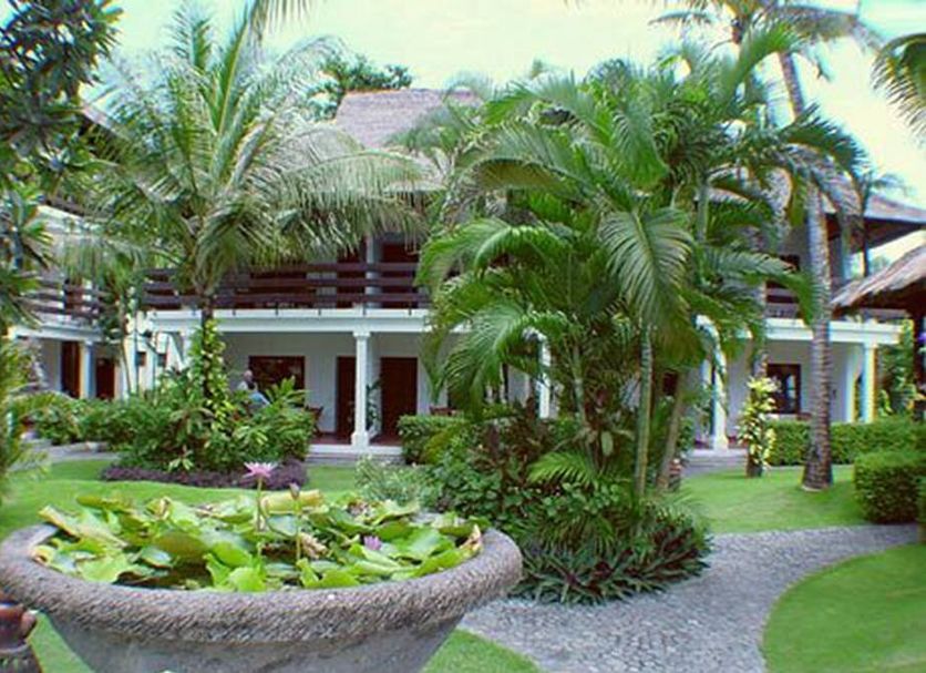 Palm Garden Hotel in Denpasar with tropical gardens, a lily pond, and a palm-lined walkway