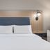 Candlewood Suites Houston (The Woodlands) By IHG guest room with a neatly made bed and wall-mounted lamps