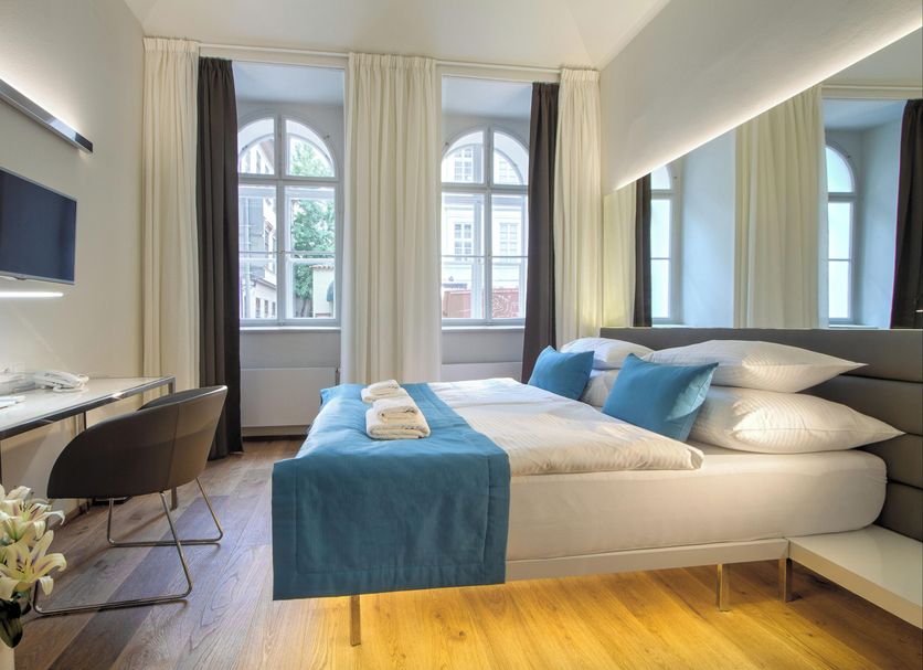 Bishop's House Prague guest room with king bed, blue accents, desk, and arched windows