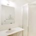 Bathroom at Budgetlodge in Oklahoma City with sink, mirror, toilet, and corner shower stall.