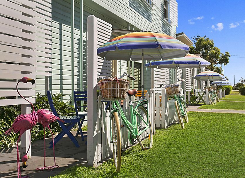 La Costa Motel in Bilinga with colorful bikes and flamingo decor beside a sunny lawn