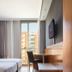 Dorma Juan De Austria in Valladolid guest room with bed, desk, wall-mounted TV and city view