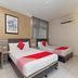 Hotel Suria Malaqa room in Malacca with two single beds, desk, chair, curtains and wall-mounted air conditioner