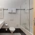 flexymotel Buchs bathroom with double sink, toilet, towel rack and glass shower in Buchs