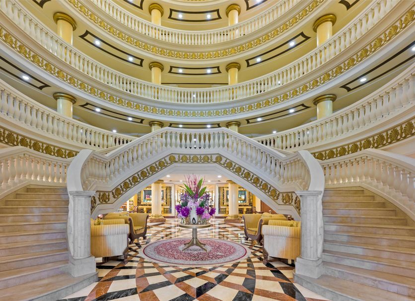 Kempinski Hotel Palm Jumeirah Dubai grand lobby with twin curved staircases and ornate chandelier ceiling
