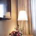 Relais Le Betulle Conegliano room with lamp, TV, flowers on wooden desk, and curtain-lit window