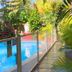 Hotel Les Bougainvilliers, Saint-Paul: tropical poolside walkway with glass railing and lush greenery