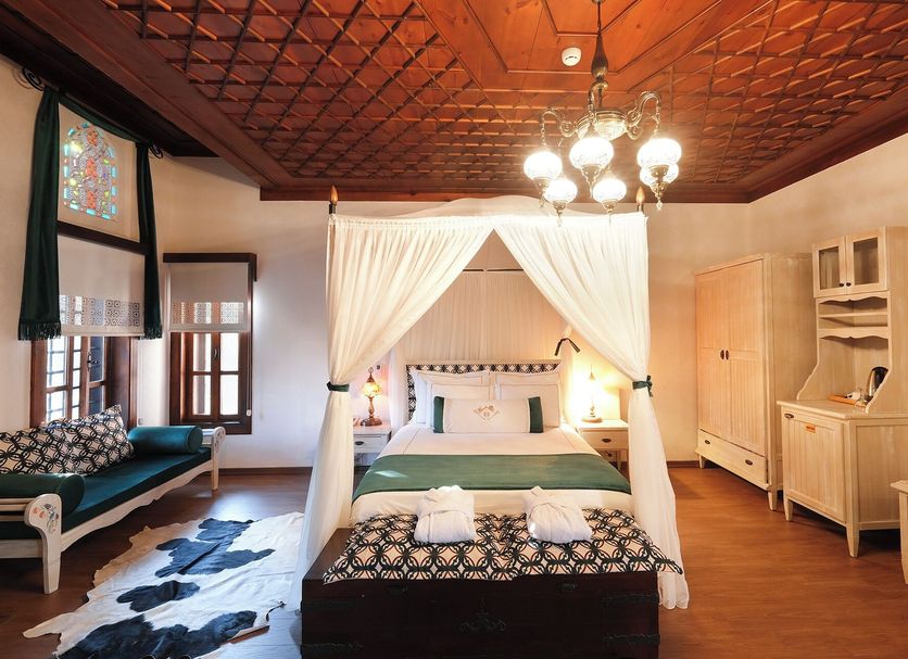 Otantik Hotel & Spa Bursa canopy bed in a wood-paneled guest room with chandelier and lounge seating