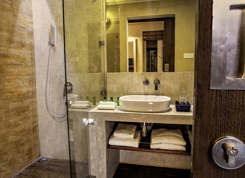 Sevana City Hotel Kandy bathroom with glass shower, vessel sink, mirror, and wood-look floor