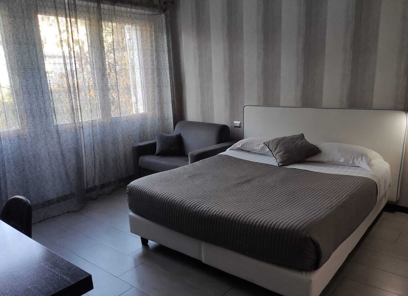 B&B Il Granello Di Senape in Rome bedroom with bed, armchair, lamp and sheer curtains