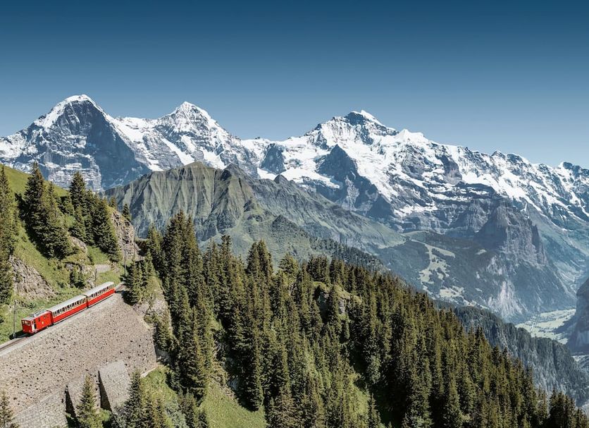 Hotel Krebs Interlaken with alpine mountain views and a red train crossing a forested mountainside