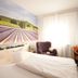 Hotel Haus Schons in Mettlach guest room with large lavender mural, bed, armchair and window