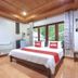 OYO 75353 Loy Chalet Resort room in Nakhon Si Thammarat with bed, balcony doors and wood ceiling