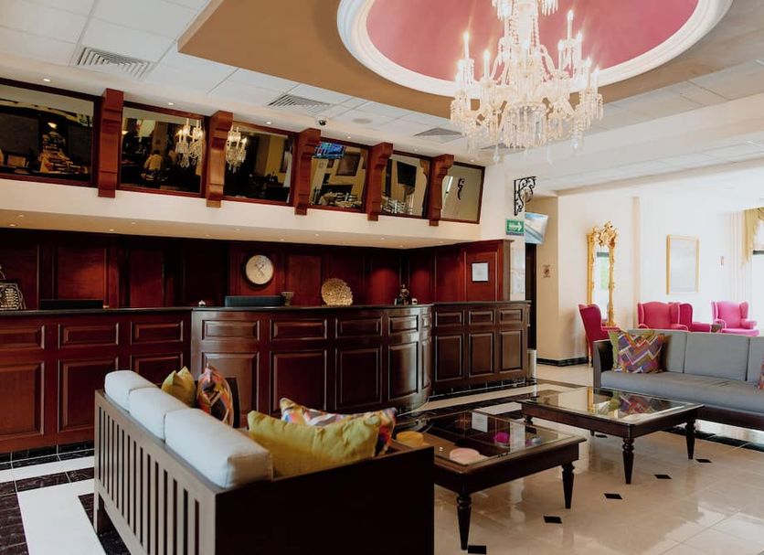 Hotel Plaza Campeche lobby with chandelier, red-accented reception bar, and seating area in Campeche