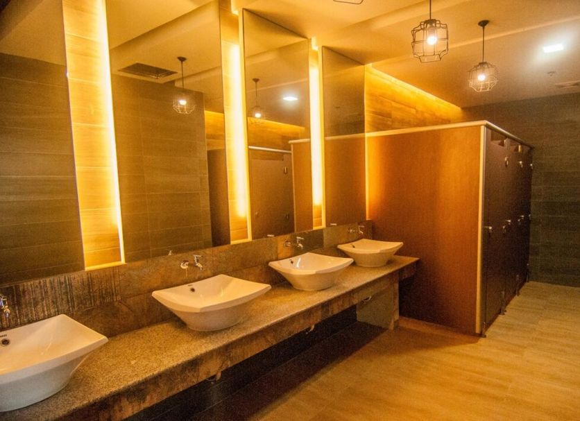 Big Hotel Suites Mandaue City restroom with vessel sinks, lit mirrors and private stall partitions