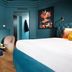 Three Corners Hotel Art Budapest room with teal walls, king bed, two chairs and wall art