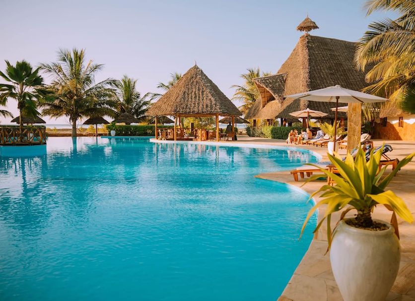 White Paradise Zanzibar in Pongwe with a tropical pool, thatched-roof huts, and palm trees