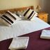 The Kings Arms London bedroom with double bed, purple throw and folded towels by the window