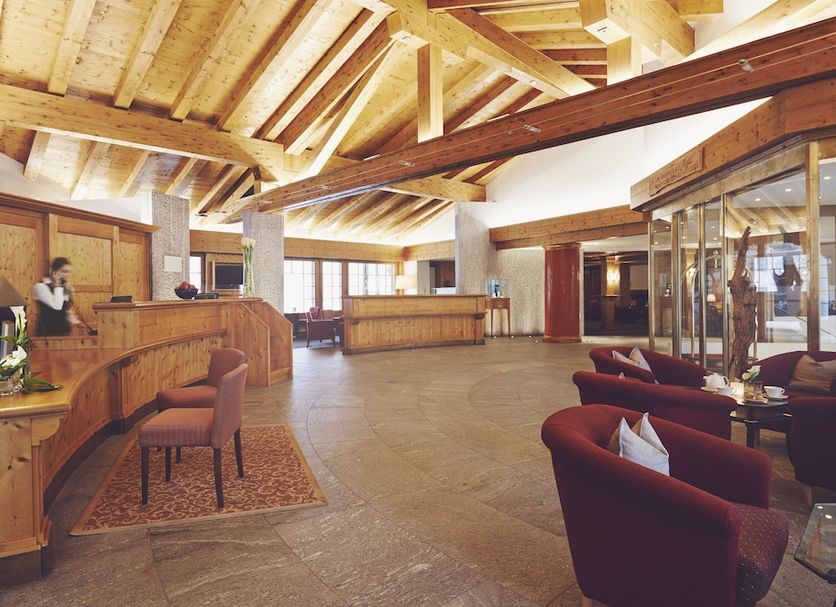Hotel Waldhuus in Davos lobby with wooden reception desk, vaulted ceiling, and seating area