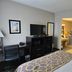Baymont by Wyndham Janesville room with desk, TV, dresser and open bathroom doorway