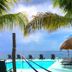 Blue Angel Resort, Cozumel: oceanfront pool with lounge chairs, palm trees and thatched palapa by the sea