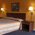 Executive Inn Rocky Top guest room with king bed, bedside lamps and framed wall art