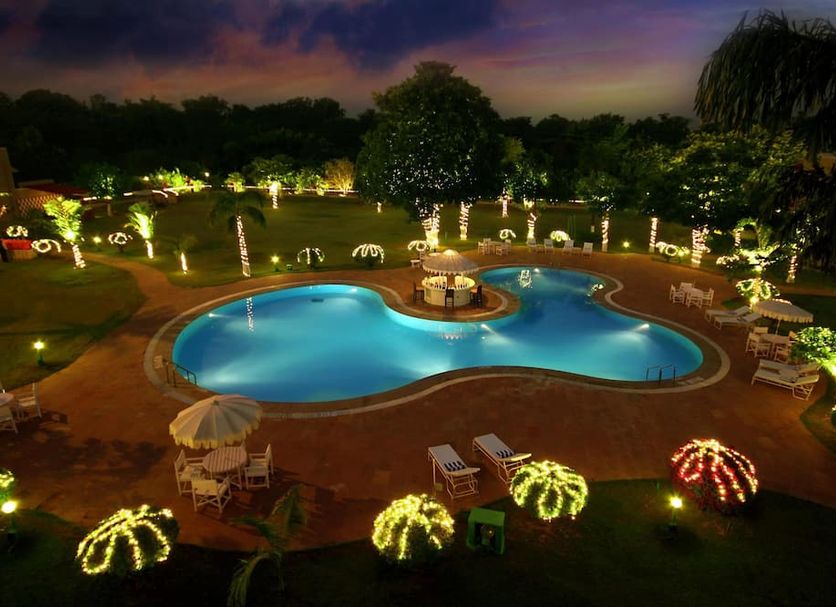 Clarks Khajuraho pool lit at night with landscaped gardens and lounge chairs in Khajurāho