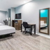 Scottish Inns & Suites - Kingwood guest room in Humble with two beds, TV, desk and full-length mirror