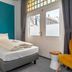 Villahotel Vlissingen guest room with single bed, teal accent wall and French doors to the street
