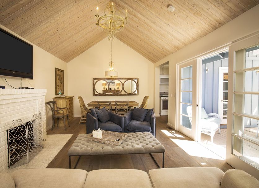 La Casa del Camino in Laguna Beach lounge with vaulted wood ceiling, fireplace, sofa, and French doors to patio