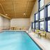 Indoor pool at City Express by Marriott Bemidji with tall windows and yellow seating