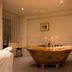 Badehaus Goor in Putbus spa bathroom with copper bathtub, shower, and tiled walls