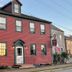 Bailey House in Annapolis Royal, red clapboard hotel exterior with lit windows and white front door
