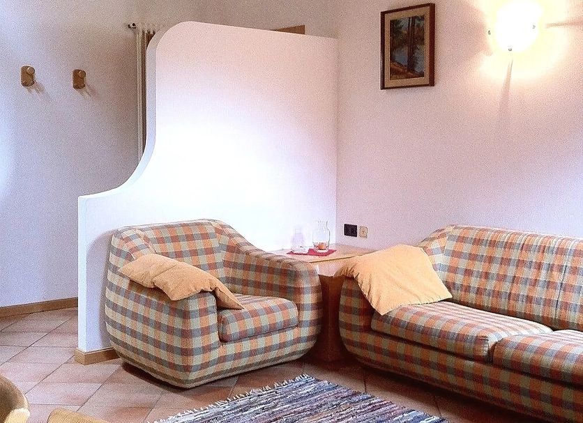 Borcanela Apartments in Moena: cozy living room with plaid sofa, armchair, and tiled floor