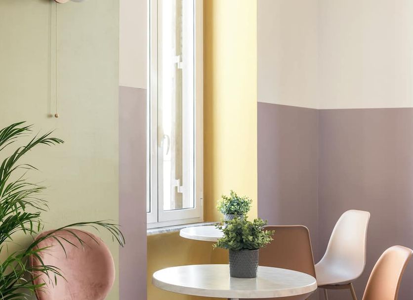 Hotel Infinito Rome lounge with round tables, chairs, potted plant and tall window light
