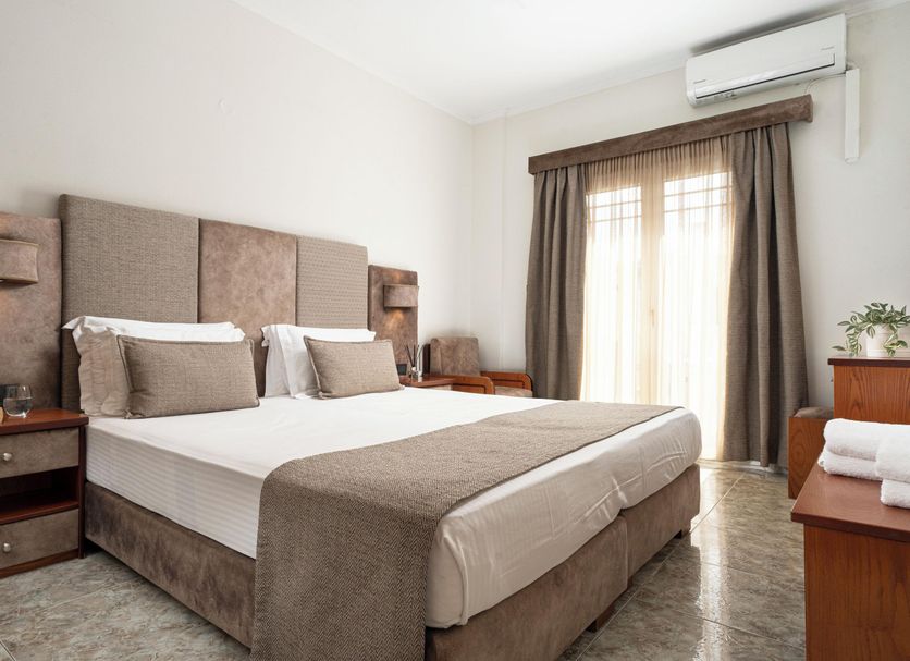 Hotel Dionysis Studios in Adamantas bedroom with double bed, bedside lamps and balcony door