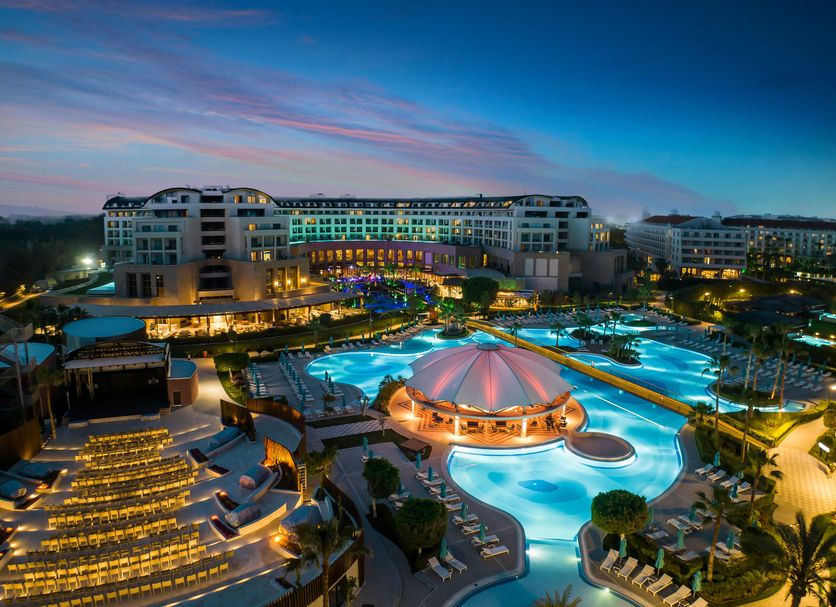 Kaya Palazzo Golf Resort in Belek with illuminated pools and resort buildings at dusk
