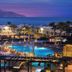 Charmillion Club Resort in Sharm el-Sheikh with a lit pool, palm trees, and sea view at dusk