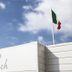 Hotel La Baia in Diano Marina with a rooftop Italian flag and beach sign against blue sky