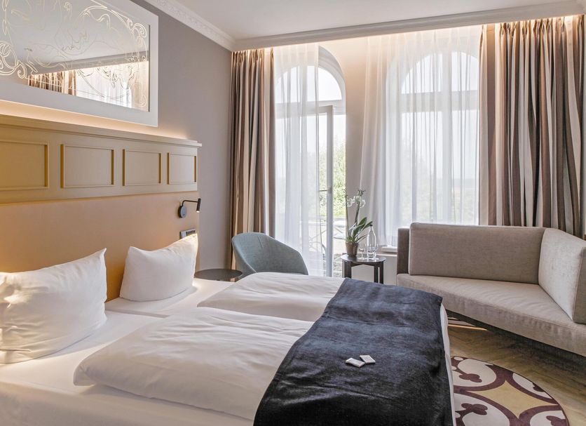 Seetelhotel Ostseehotel Ahlbeck in Heringsdorf: bright hotel room with twin bed, sofa and arched windows