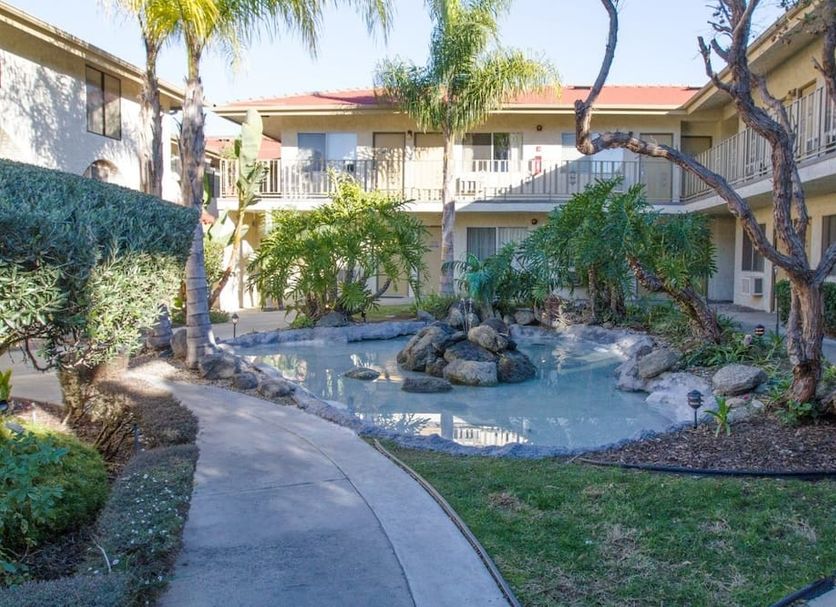 California Suites Hotel San Diego courtyard with small pond, palm trees and two-story exterior