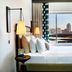 The Casso, Raleigh, a Tribute Portfolio Hotel room with city-view window and bed by the bedside lamps